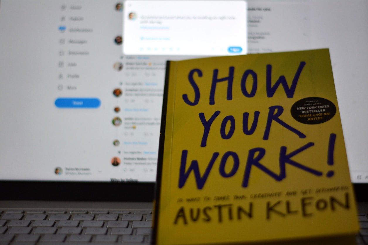 Yellow notebook with the text Show Your Work on a desk